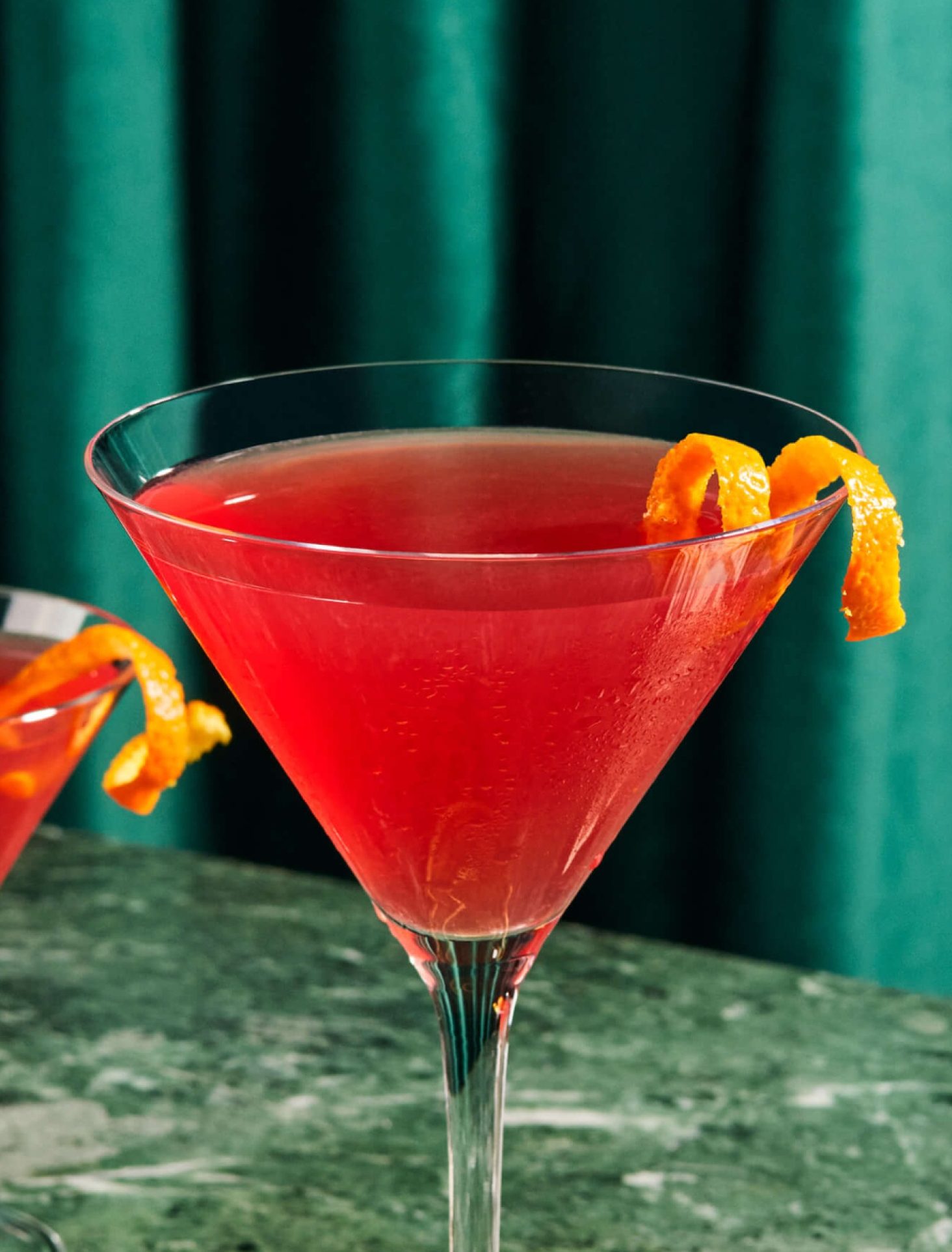 A Cosmopolitan cocktail in a martini glass with orange peel garnish